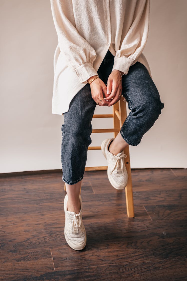 A Person In Denim Jeans Sitting On A Stool