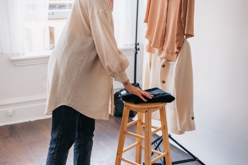 Free A person arranging clothes indoors, showcasing fashion and interior design elements. Stock Photo