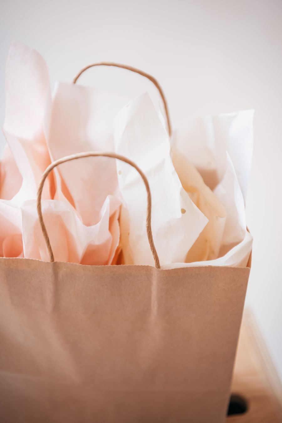 A kraft carrier bag filled with soft white and blush tissue