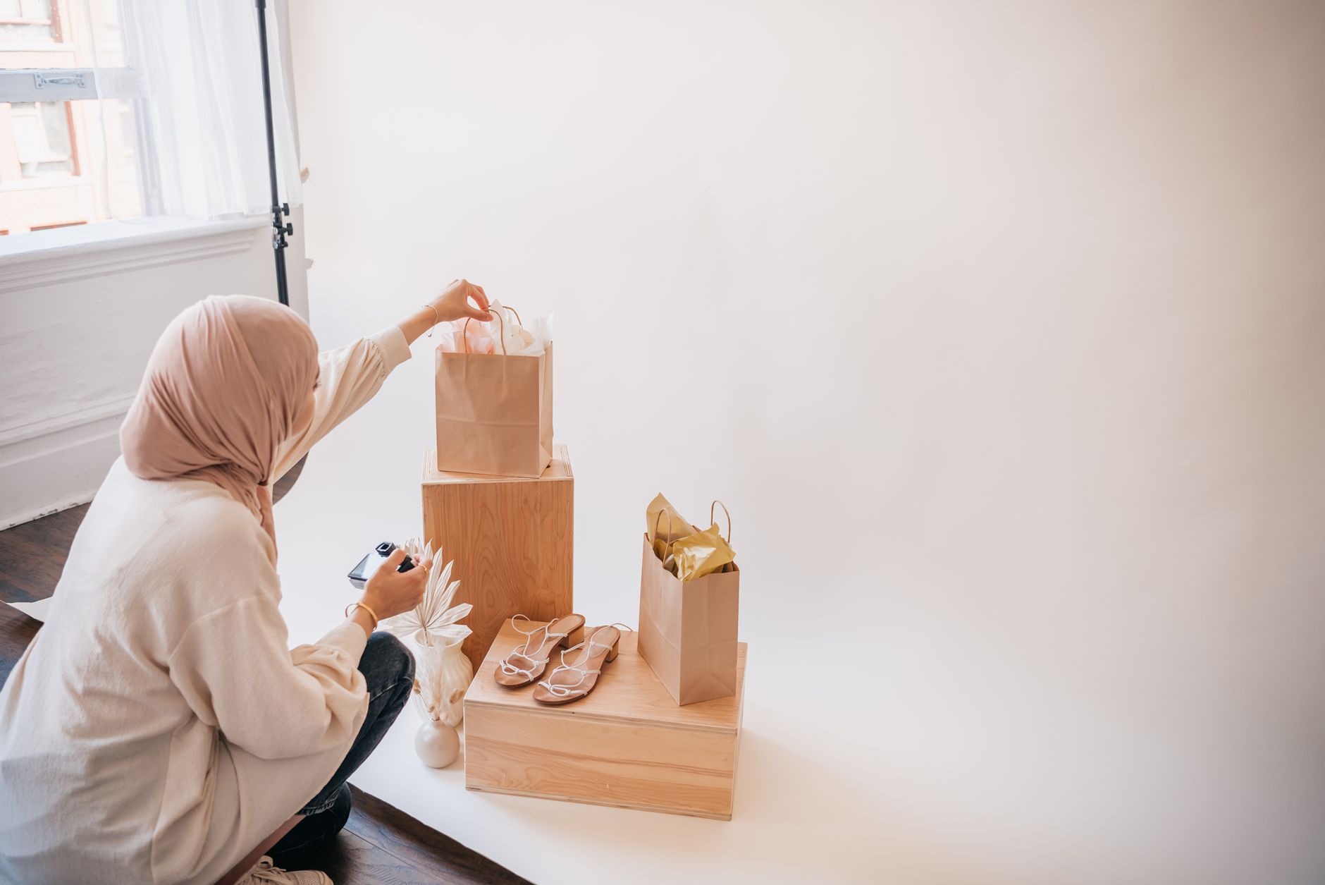 Muslim woman organizing paper bags with shoes in a studio setup. Perfect for ecommerce or lifestyle imagery.