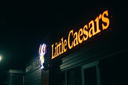 Free A dimly lit image of a Little Caesars restaurant sign glowing in the night. Stock Photo