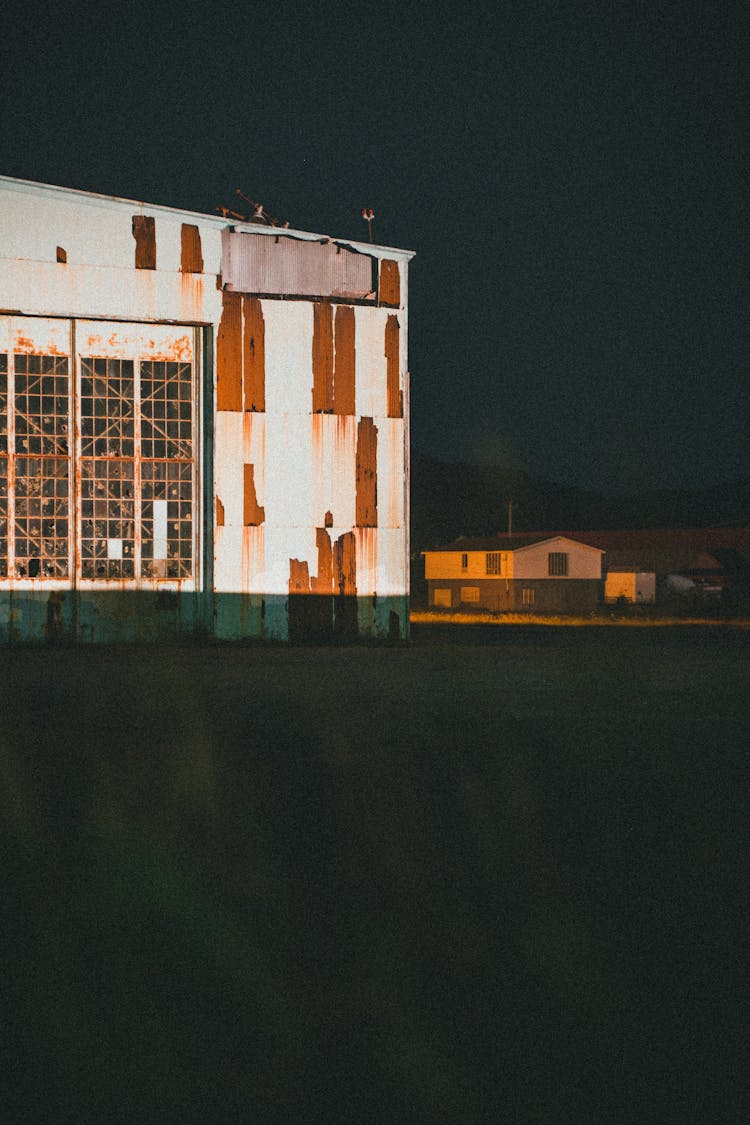 Rusty Exterior Of A Warehouse Illuminated At Night 