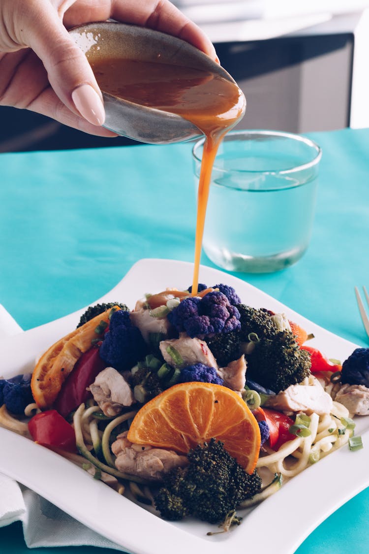 Person Pouring Sauce On Food