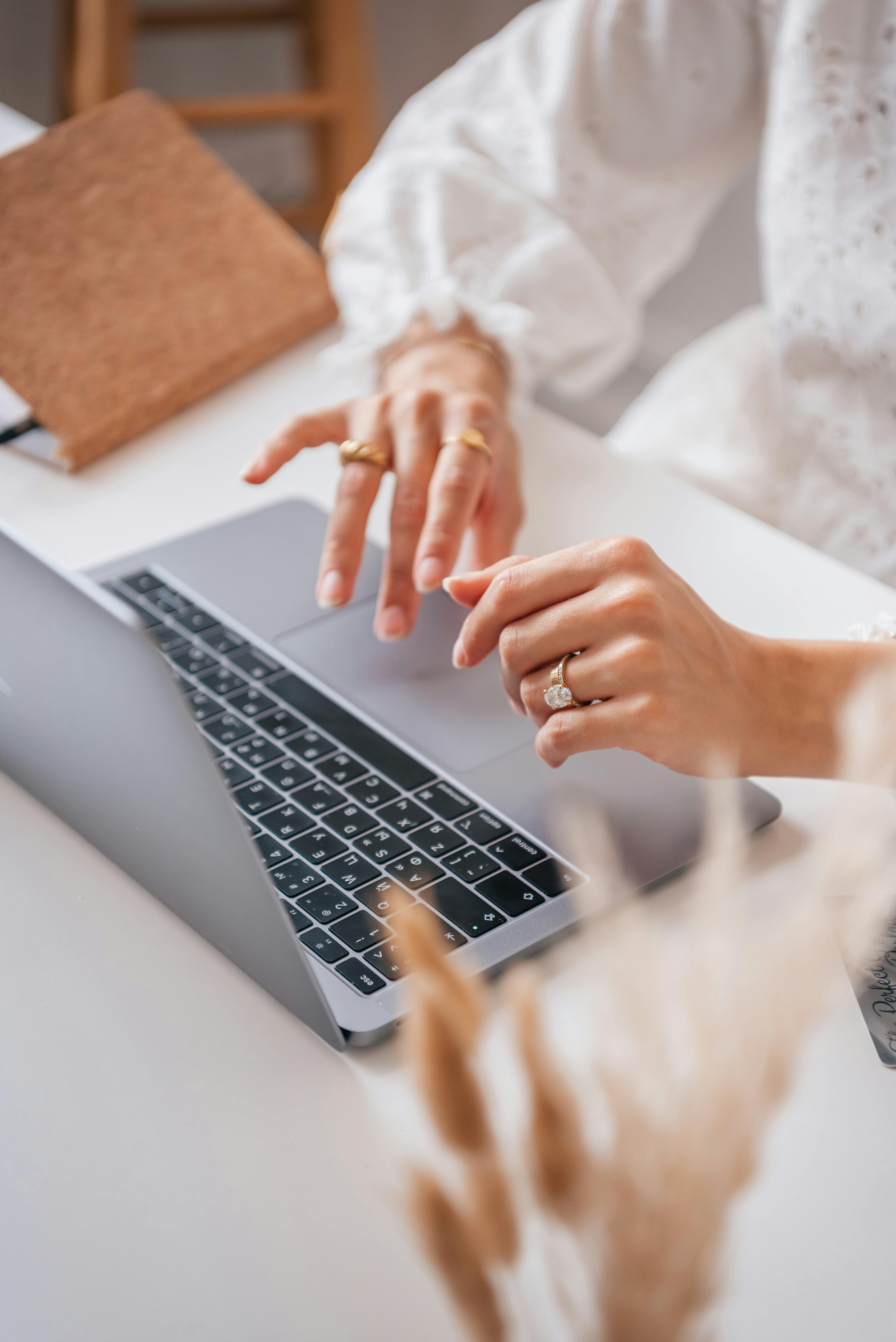 a person with rings typing on a laptop