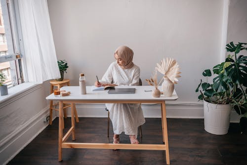 Free Person Sitting on Chair Writing on a Notebook Stock Photo
