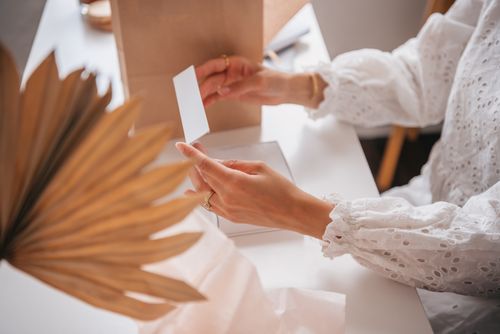 Free A person with lace long sleeves opening a white box at a table. Stock Photo