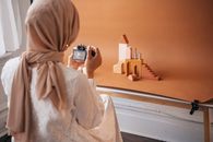 Person in White Hijab Taking Photo of Brown Concrete Building