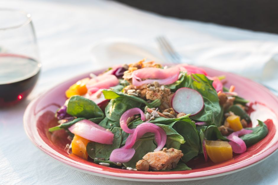 A white platter with overlapping thin slices of golden beets and orange segments, scattered with slivers of red onion and fresh mint leaves, lightly drizzled with dressing.
