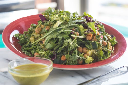 Healthy vegetable salad with chickpeas and green dressing on a table.