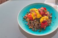 Vibrant quinoa salad topped with grilled vegetables on a blue plate.