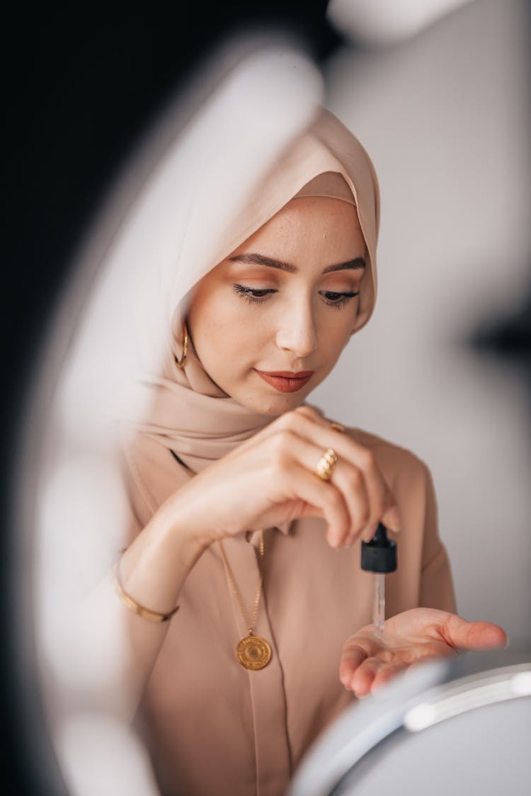 A Hijab Woman Holding A Cosmetic Dropper