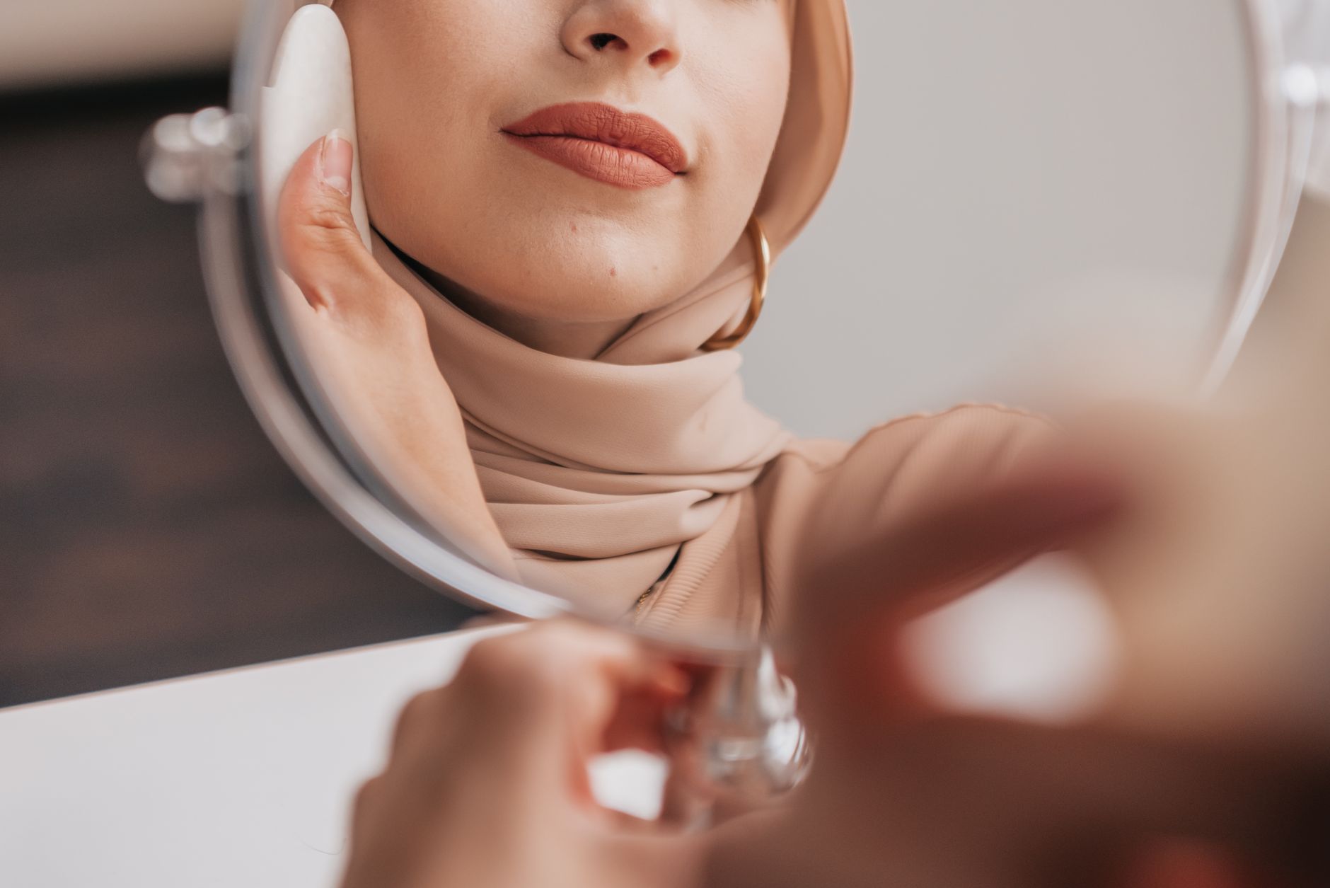 Close-up of a woman in hijab looking in the mirror, highlighting beauty and reflection.
