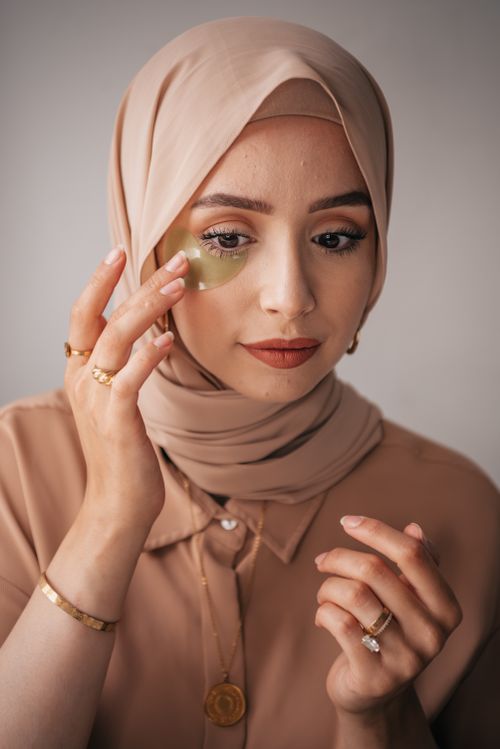 Free Close-up of a woman in a hijab applying an under eye patch for skincare. Stock Photo