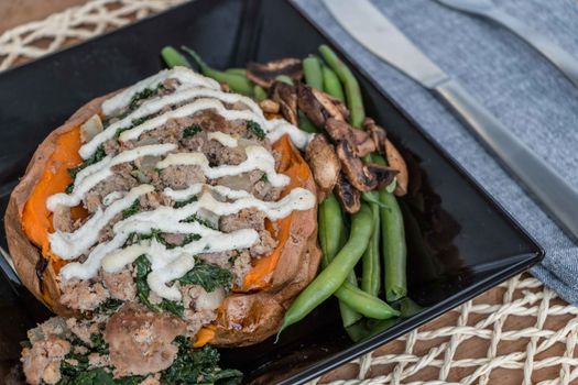 Delectable stuffed sweet potato served with green beans and mushrooms, perfect for a hearty meal.
