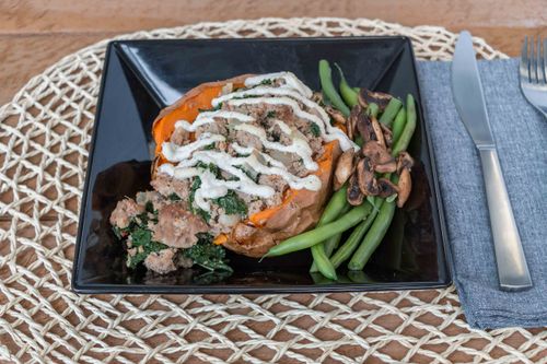Free A savory stuffed sweet potato dish with green beans and mushrooms on a black plate. Stock Photo