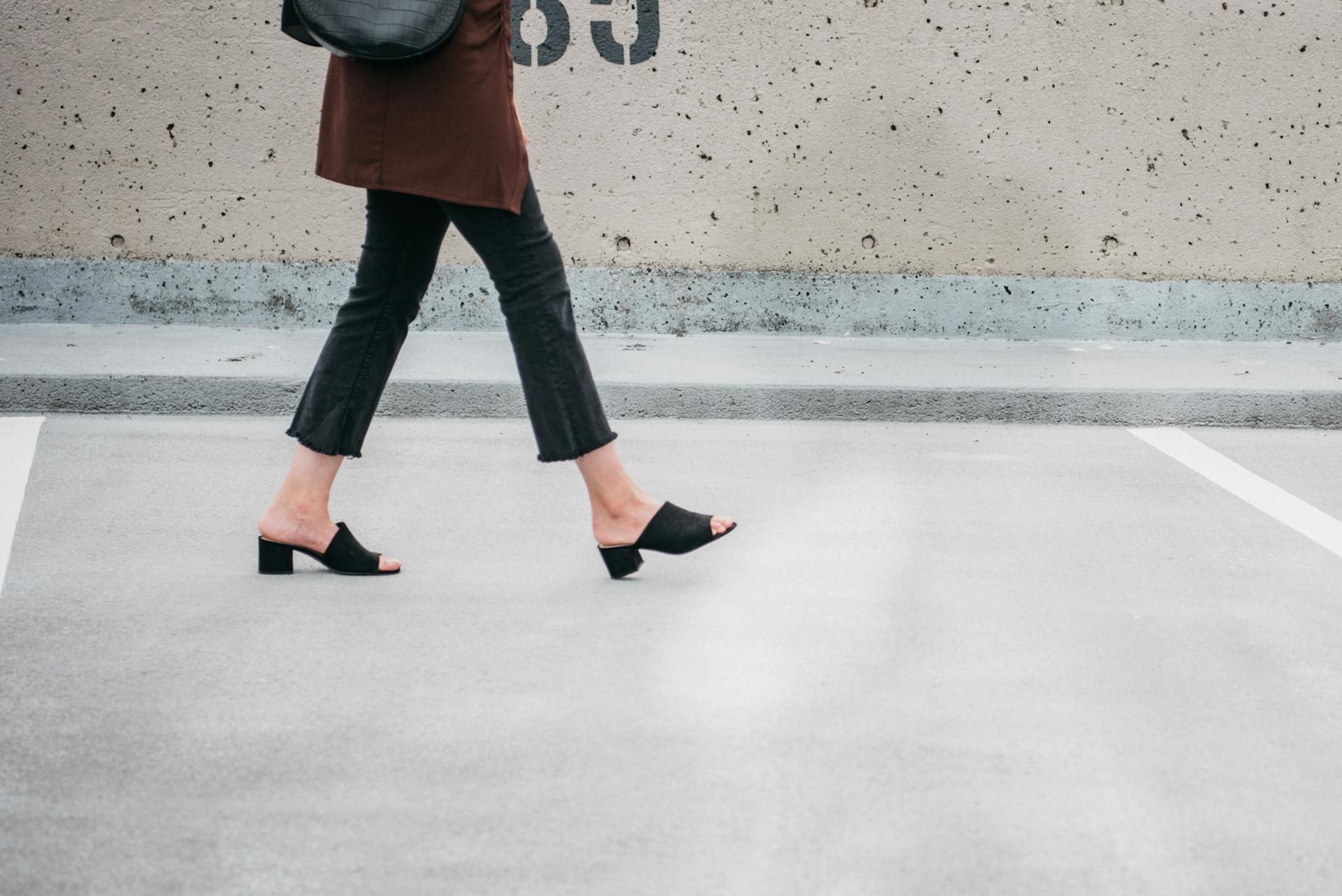 A Person Walking Wearing a Black Sandals with Heels