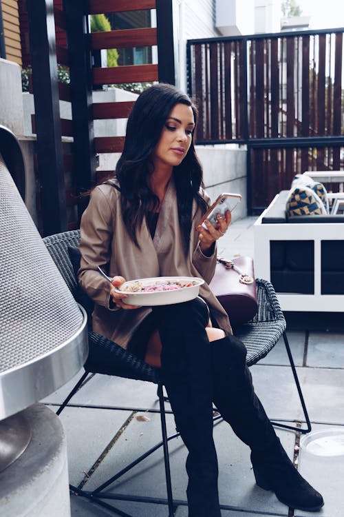 Woman Sitting on a Chair While Holding Cellphone