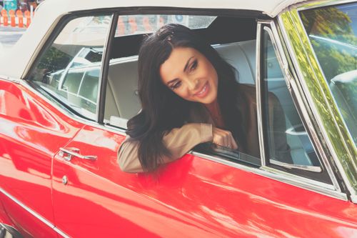 Free Woman sitting and smiling in a red classic cabriolet car. Stock Photo