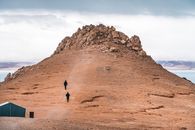 Person in Black Jacket Walking on Brown Rock Formation