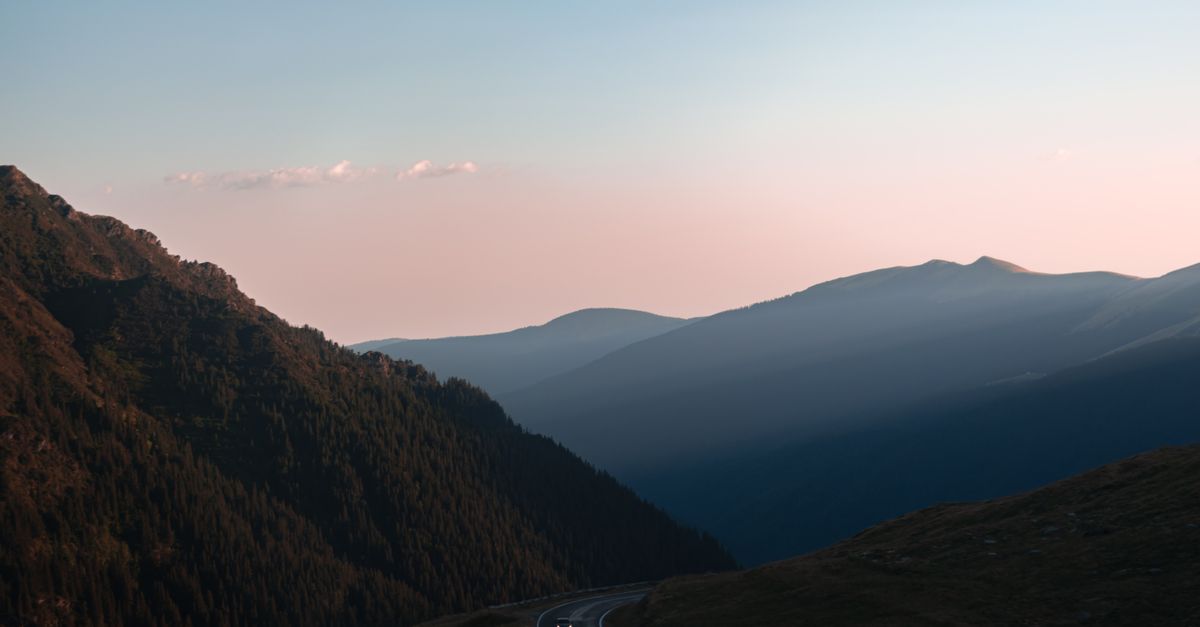 Scenic view of a winding mountain road during sunset in the Romanian Carpathians.