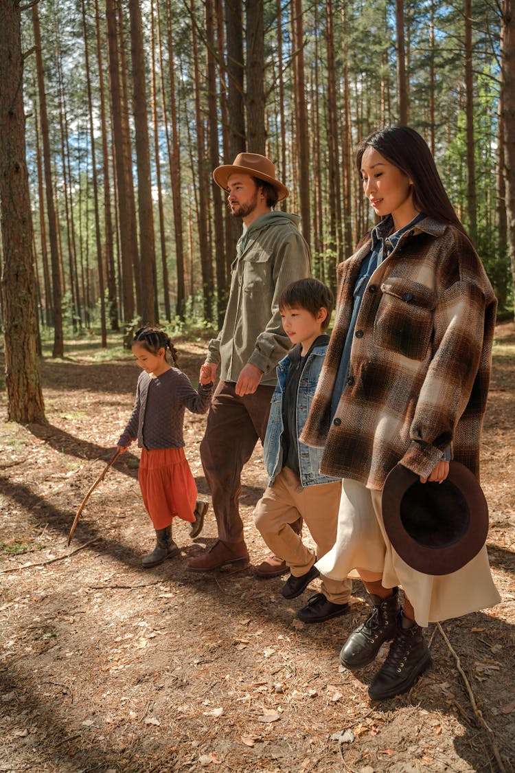 A Family Walking Near The Woods While Holding Hands