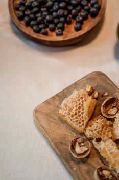 Honeycomb, walnuts, and blueberries on a wooden board, creating a rustic and healthy snack aesthetic.