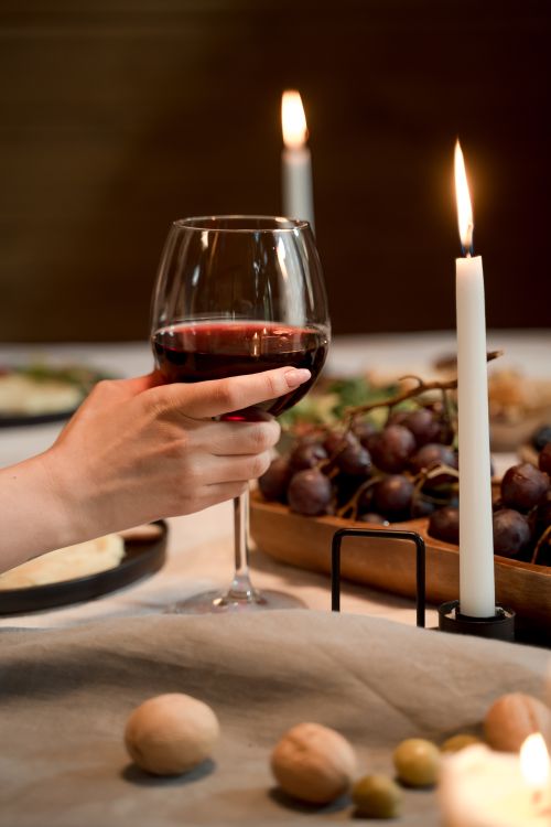 Free Elegant dining setup featuring wine, candles, and a cozy atmosphere for a romantic evening. Stock Photo