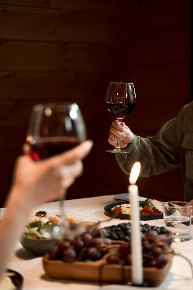 A Couple Holding Glasses With Wine