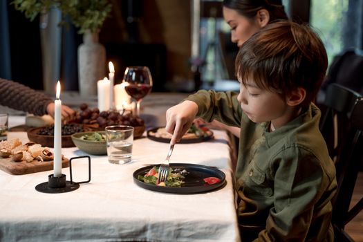 A young boy dining with family at a cozy indoor dinner setting.