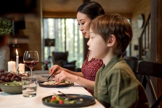 Mother and son enjoying a meal indoors, capturing family time with warm ambiance.
