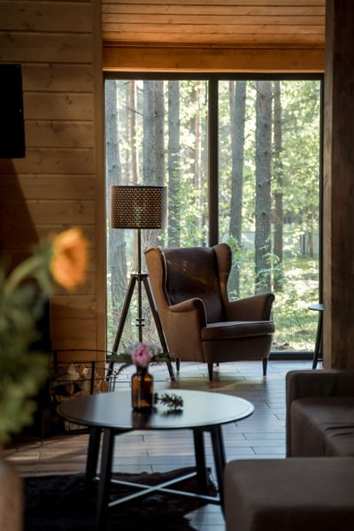 Reading corner with a leather chair beside floor-to-ceiling glass — photo by Ron Lach on Pexels