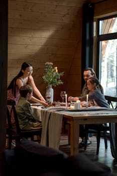 A family enjoys quality time during a warm dinner in a rustic, cozy cabin atmosphere.