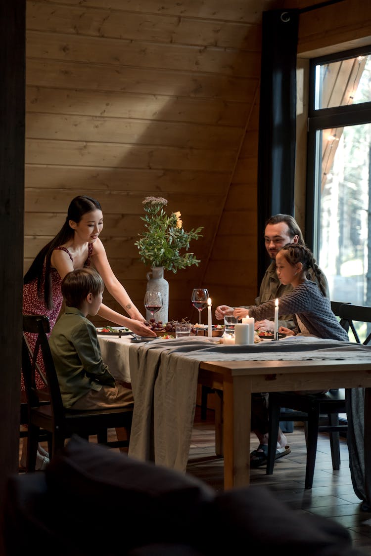 A Woman Serving Food On Her Family