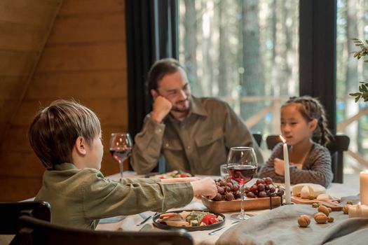 A family enjoying a dinner with fresh fruits and wine in a cozy cabin setting.