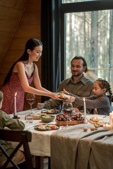 A family enjoying a warm dinner together in a cozy cabin, surrounded by nature.