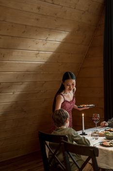 A family enjoys a warm dinner by candlelight in a cozy wooden cabin, creating a serene atmosphere.