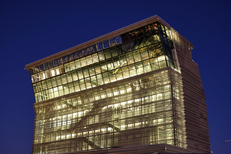 Illuminated Office Glass Building On Blue Sky