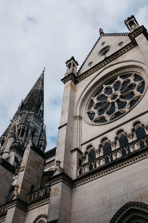 Free Stunning low-angle view of a Gothic cathedral facade with intricate architecture and cloudy sky backdrop. Stock Photo