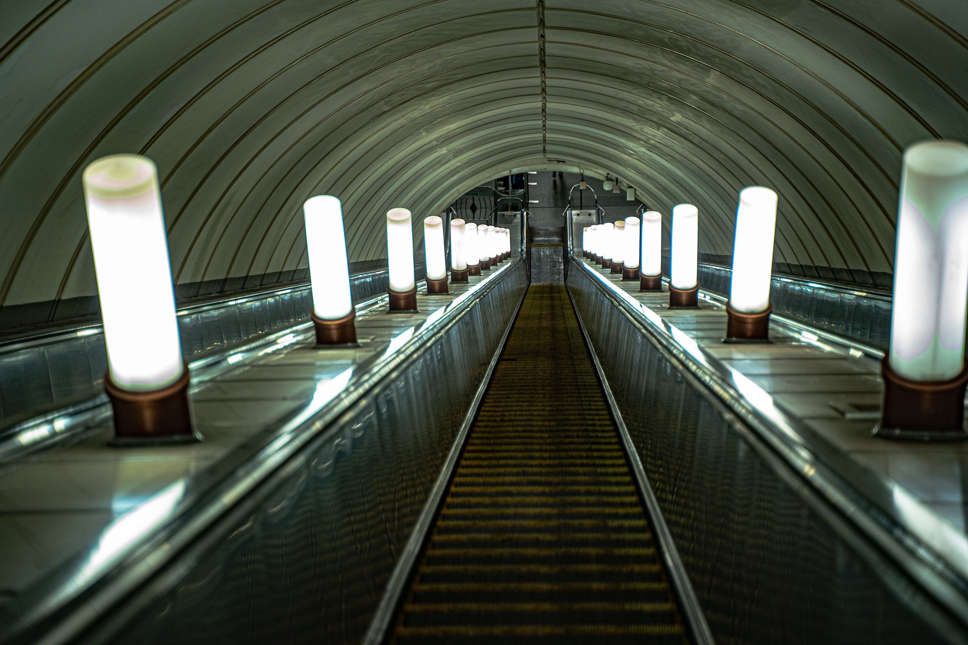 A view down an illuminated escalator tunnel inside the Moscow Metro station.
