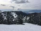 在多云的冬季天空下，可以看到雪山景观和海景