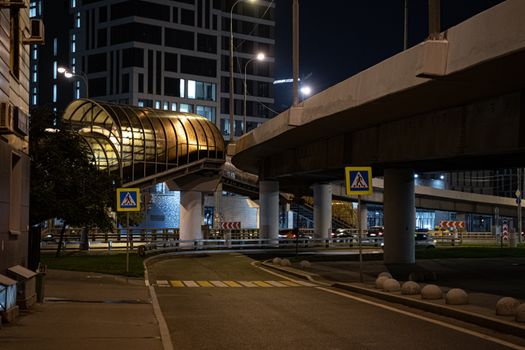 Illuminated overpass and city architecture captured at night with no pedestrians on the road.