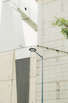 Minimalist view of a modern building facade with a street light and greenery.