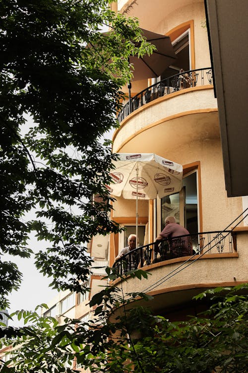 Elderly Men Sitting on the Balcony Under an Umbrella