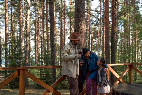 Free A family of three bonding in a serene forest setting, sharing a warm moment outdoors. Stock Photo