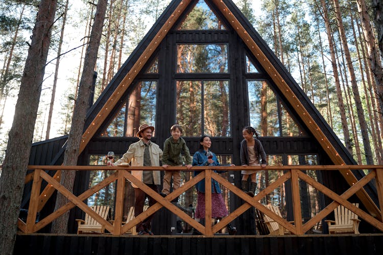 Family On Balcony Of Cabin In Forest