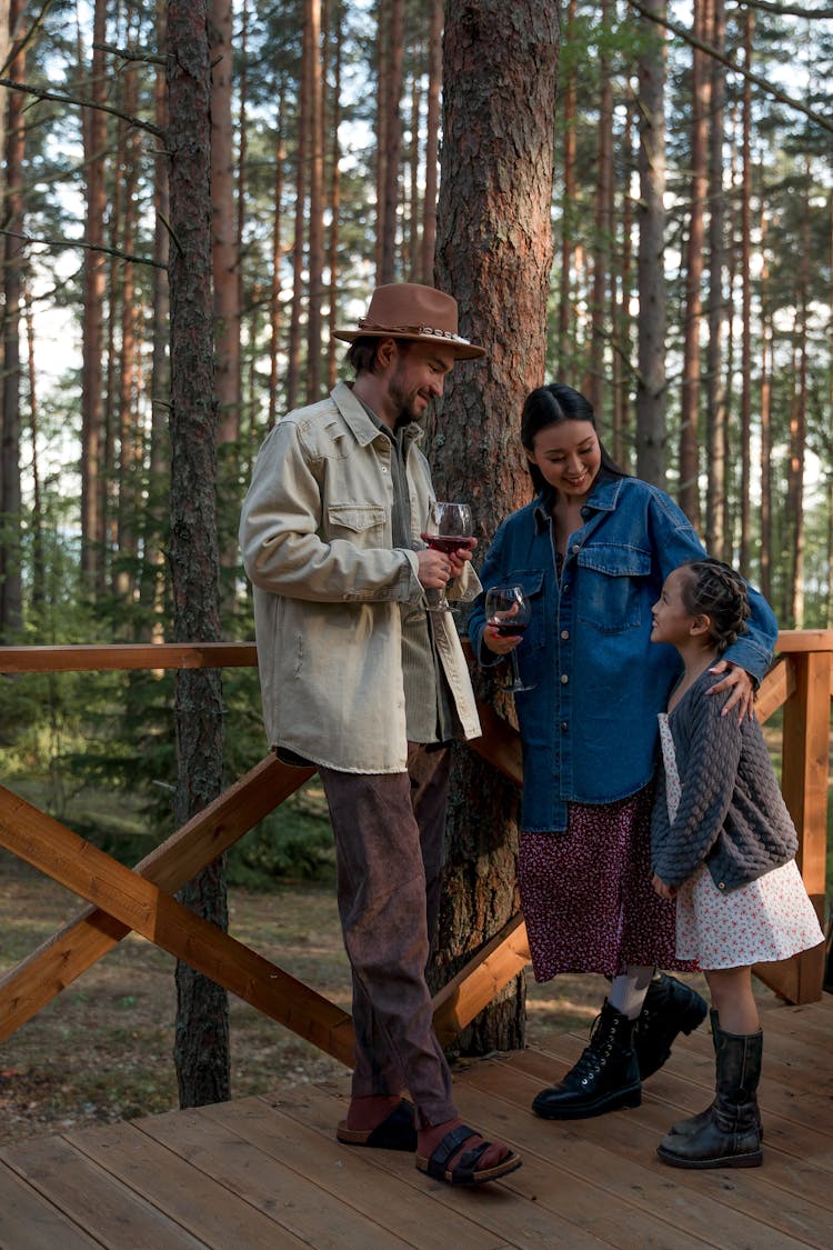 A Couple Holding Wine Glasses While Looking At Their Daughter