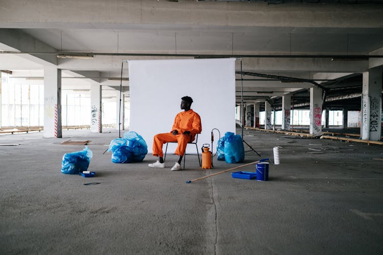 Man In Orange Clothes Sitting On Chair Looking Afar 