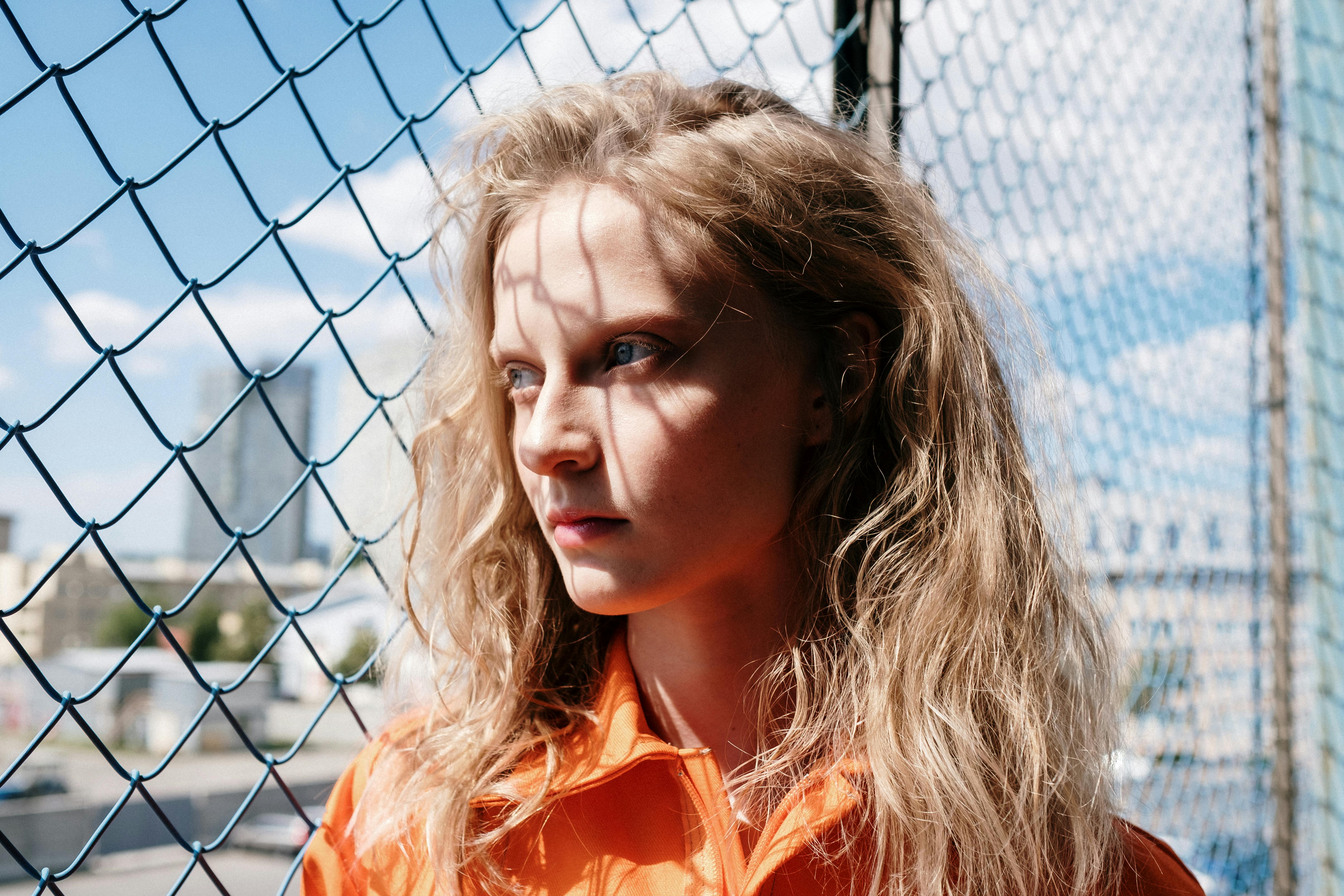 a woman in orange shirt near the chain link fence