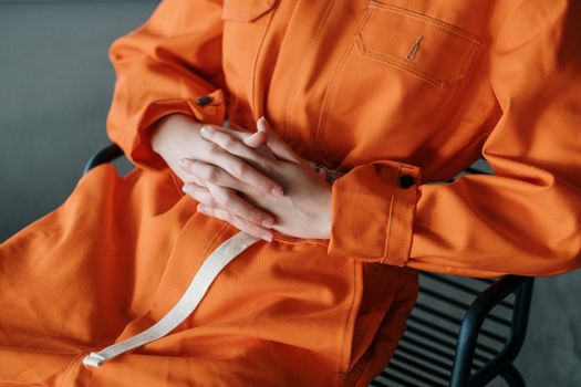 Person in Orange Jumpsuit with Hands Clasped