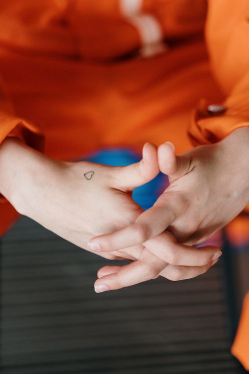 Free A close-up photo of adult hands intertwined with a small heart tattoo visible on one hand. Stock Photo
